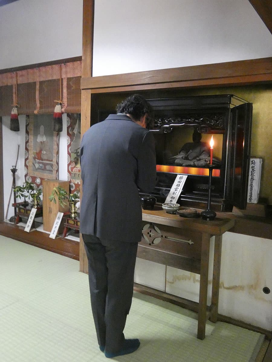 西蓮寺に伝わる柴田勝家公御木像に手を合わせる山口さん